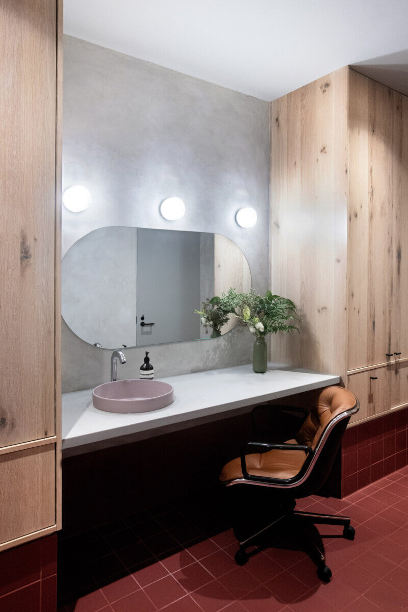 A 70s style bathroom design in a modern office building with bulb lights and oversize vanity mirror