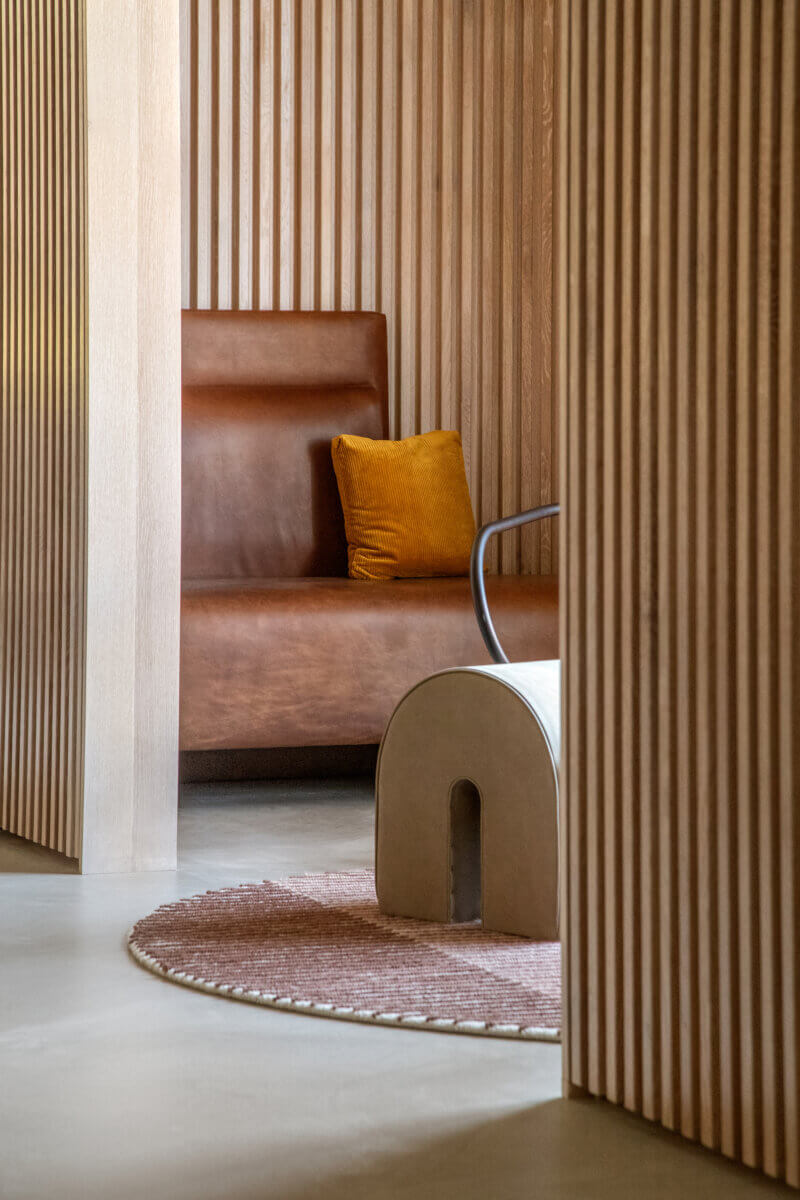 A nook with a built-in leather banquette and custom ribbed oak paneling