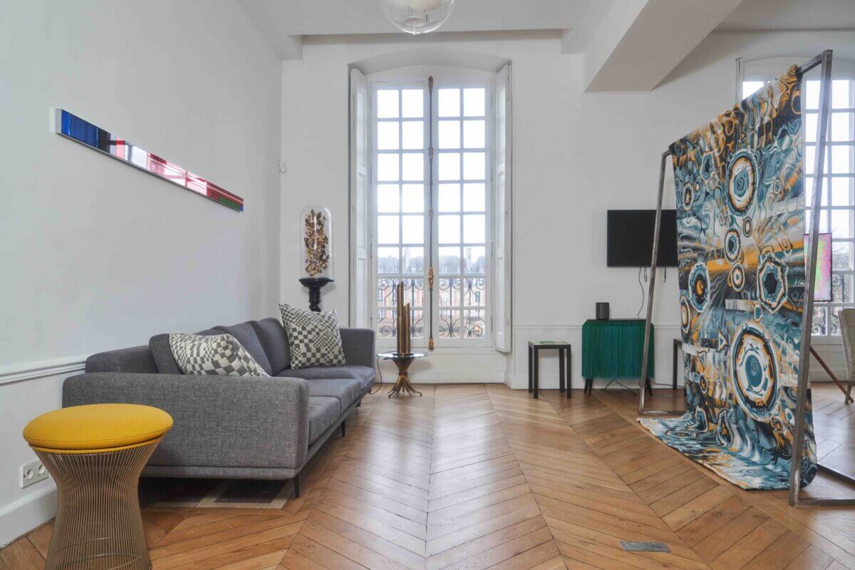 A Martin Grasser mirror from his Portraits collection sits on the wall, and a Navette tapestry, rendered from generative code by Alexis André, hangs on the right