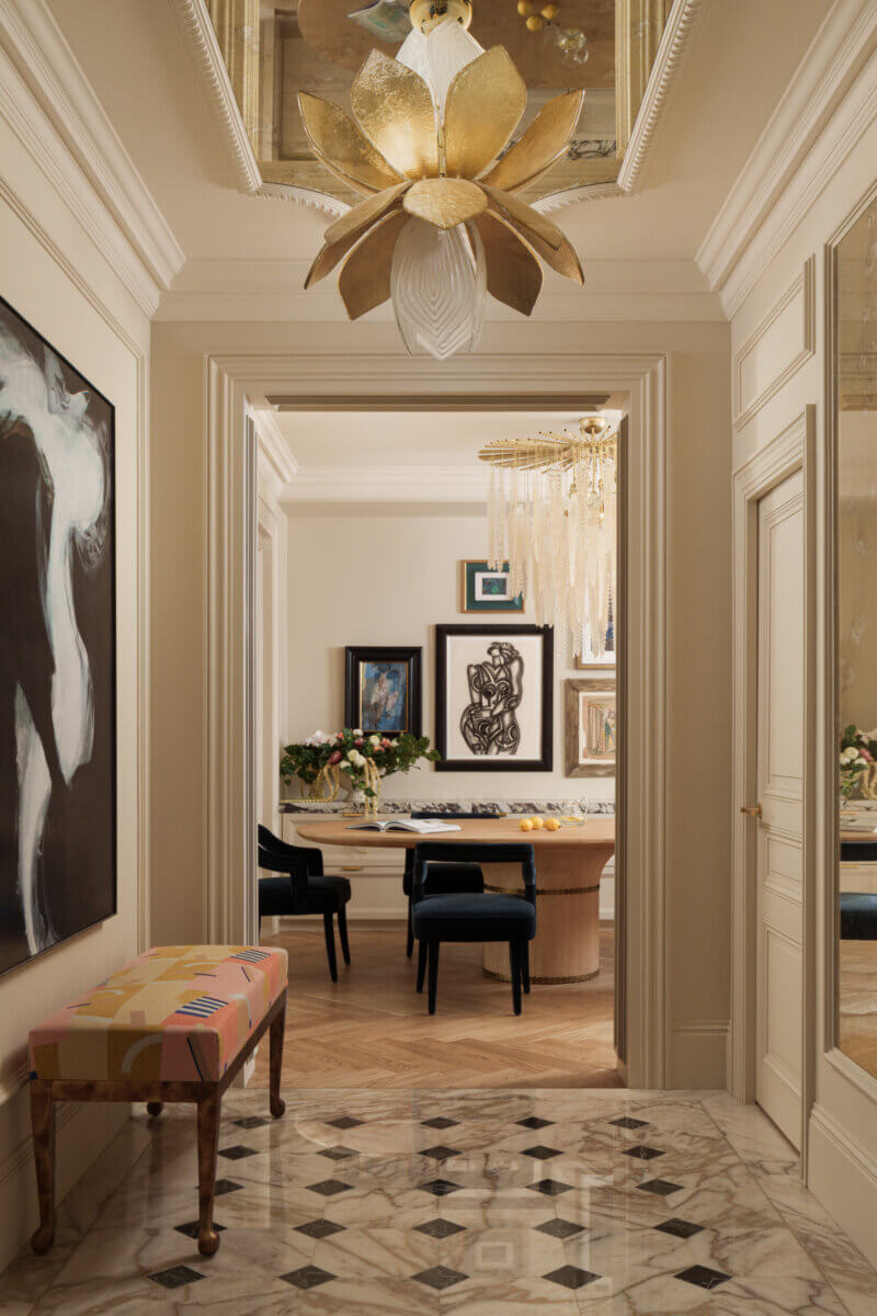 A home designed by Mark Howorth: a hallway shot, looking into a bright dining room. A gold fixture hangs to contrast darker furnishing.