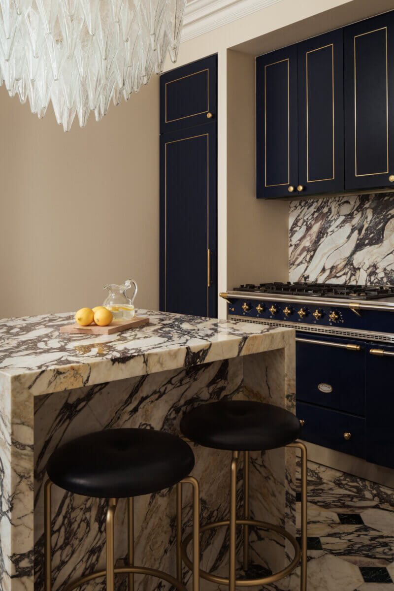 A kitchen designed by Mark Howorth: marble kitchen island and counters, with appliances and cabinets a deep noir.
