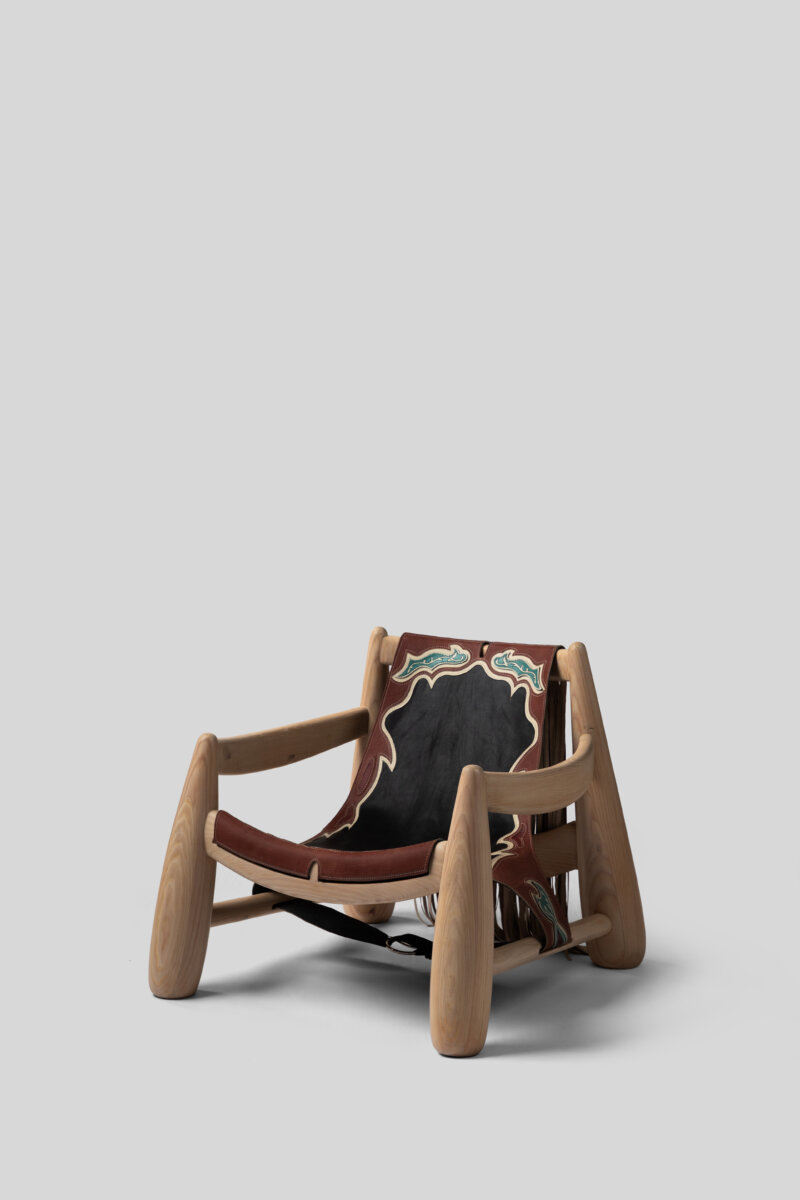 A sculptural wooden chair featuring a curved, handcrafted frame and a dark leather seat and backrest adorned with intricate turquoise, cream, and red decorative detailing.